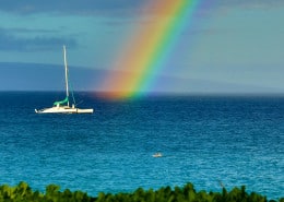 View of a rainbow and a sailboat from the beach