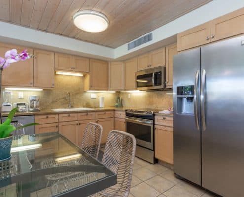 Kitchen with a refrigerator, microwave, stove, sink, and dining area.